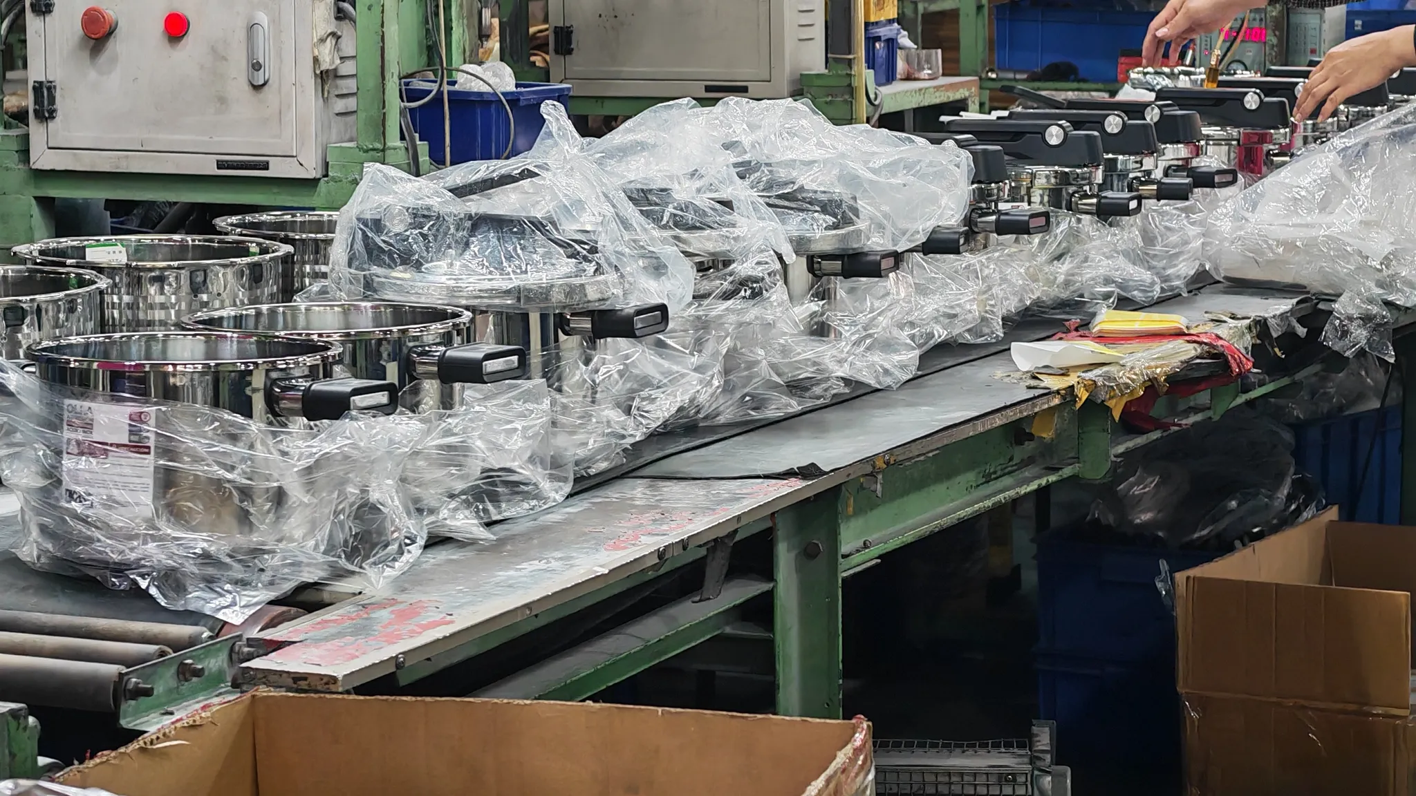 Finished stainless steel pots being bagged on a factory packing line before export cartons are sealed