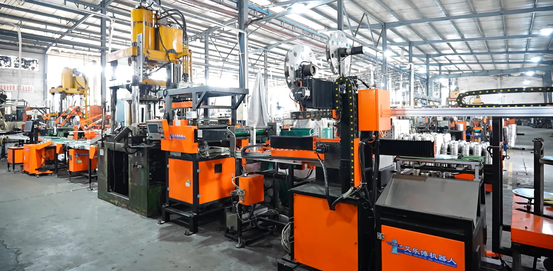 Automated stamping line deep-drawing stainless steel cookware bodies from sheet metal, with robotic transfer between stations