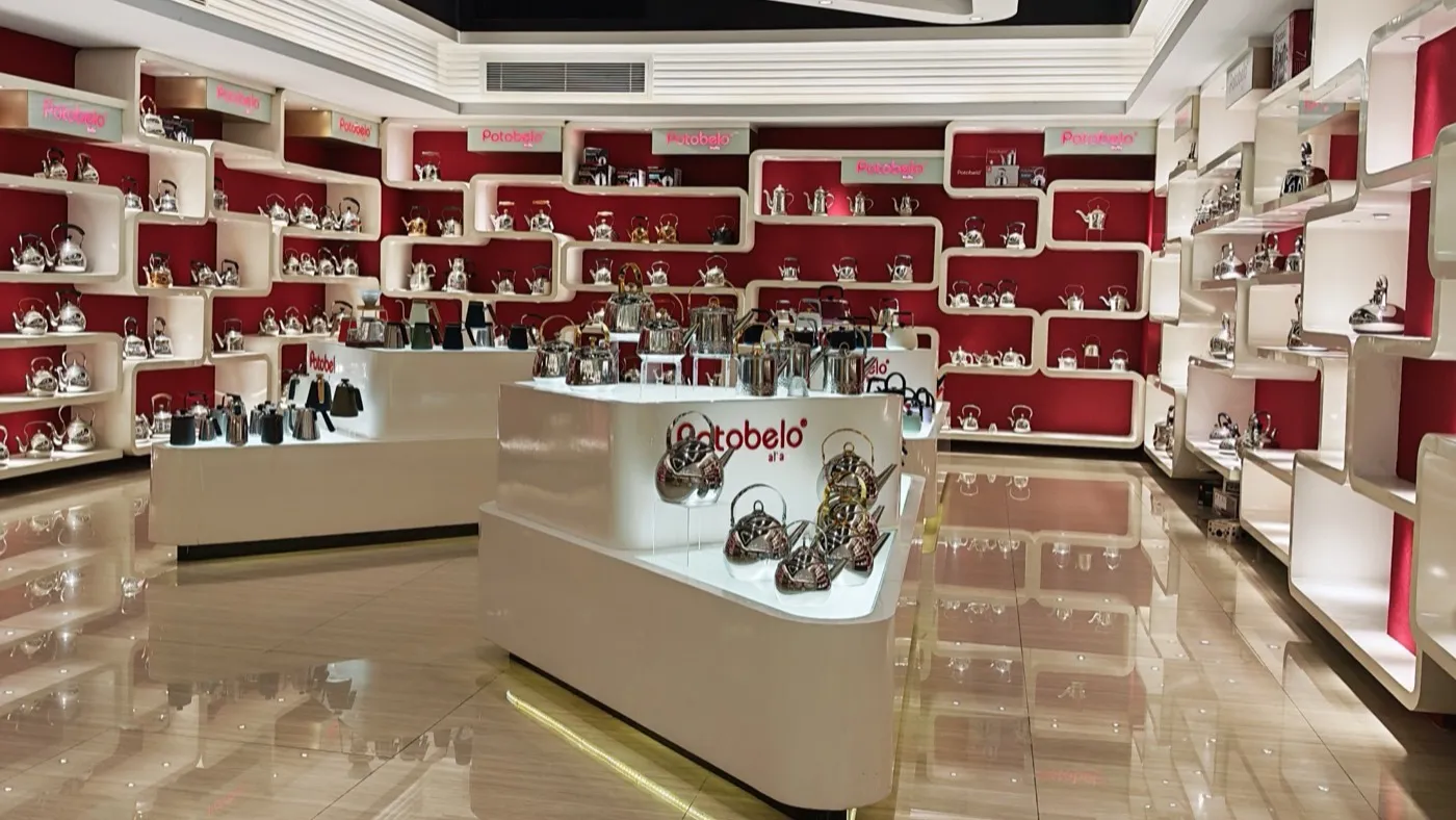 Rows of stainless steel kettles and teapots displayed on shelves in the Potobelo product exhibition hall